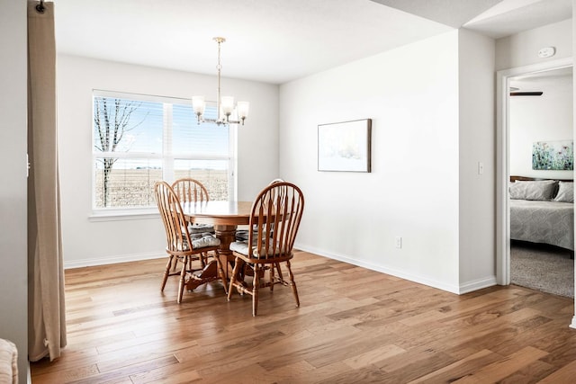 dining space featuring a notable chandelier, light wood-type flooring, and baseboards