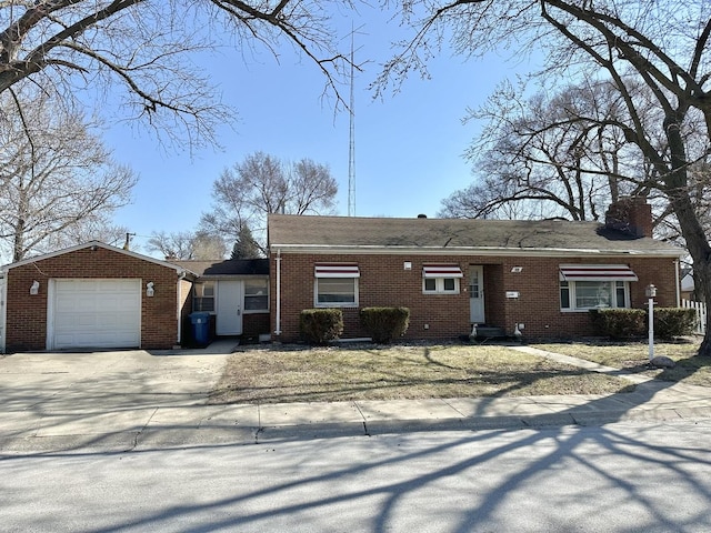 rear view of property featuring a garage, brick siding, driveway, and a chimney