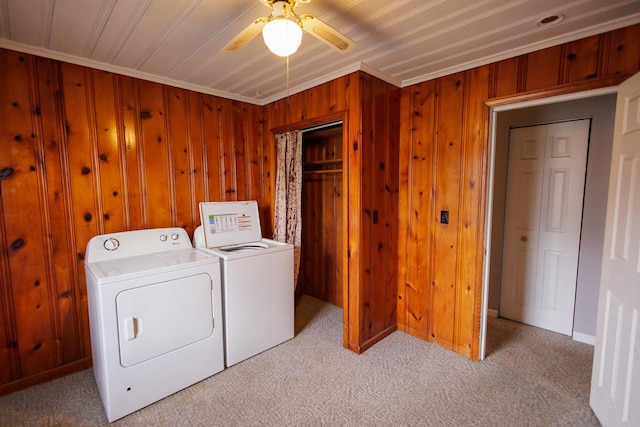 clothes washing area with washing machine and clothes dryer, carpet flooring, ceiling fan, and wooden walls