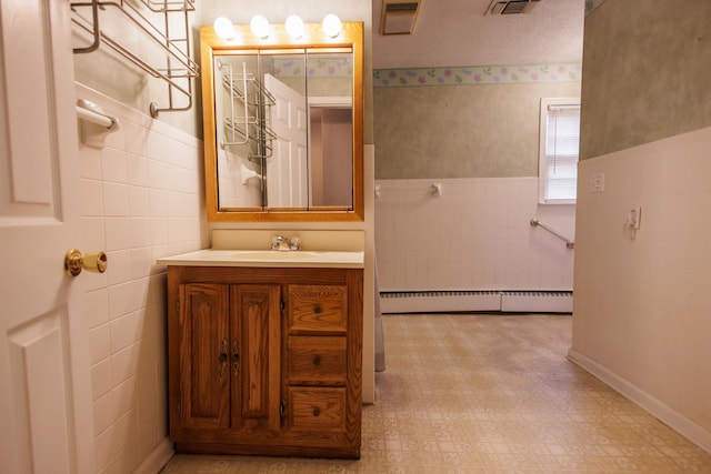 bathroom with vanity, tile walls, visible vents, and baseboard heating