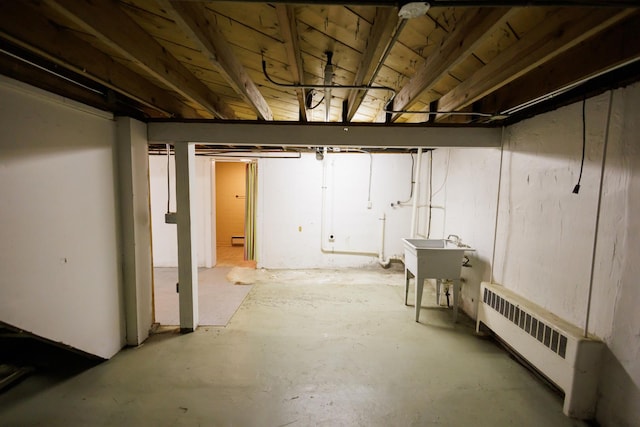 unfinished basement featuring radiator heating unit and a sink