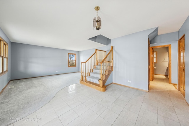 unfurnished living room featuring stairs, light tile patterned floors, baseboards, and light carpet