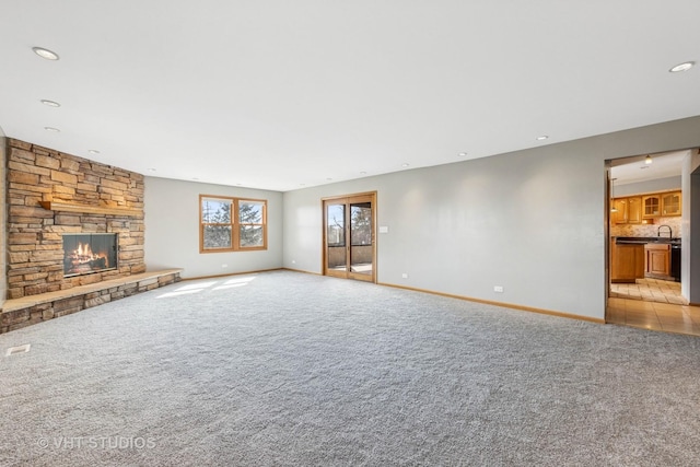 unfurnished living room featuring recessed lighting, baseboards, light carpet, and a fireplace