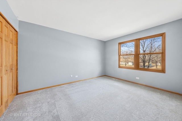 empty room featuring baseboards and light carpet