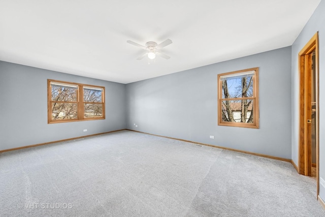 carpeted empty room with ceiling fan and baseboards