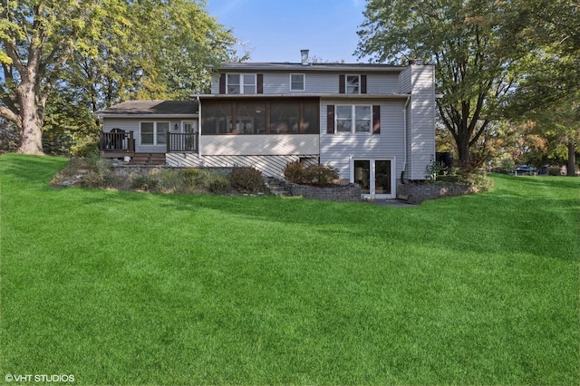 rear view of house with a lawn, a deck, a chimney, and a sunroom