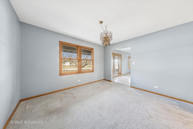 unfurnished room with visible vents, baseboards, a chandelier, and carpet flooring