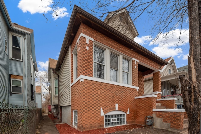 view of side of home featuring brick siding and fence