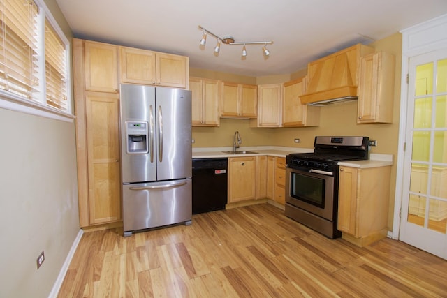 kitchen with a sink, custom range hood, appliances with stainless steel finishes, and light brown cabinetry