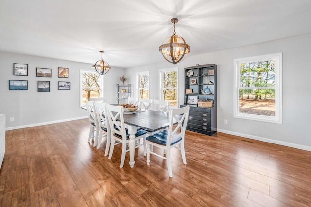 dining room with a wealth of natural light, a notable chandelier, and wood finished floors