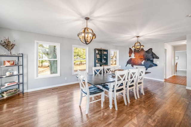 dining space featuring baseboards, a notable chandelier, and wood finished floors