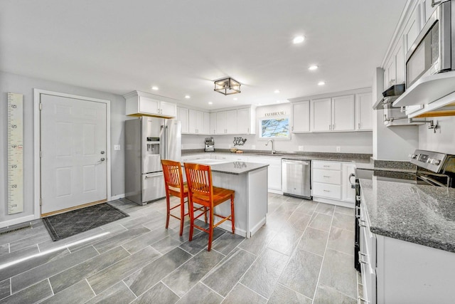 kitchen with a sink, recessed lighting, appliances with stainless steel finishes, a breakfast bar area, and white cabinets