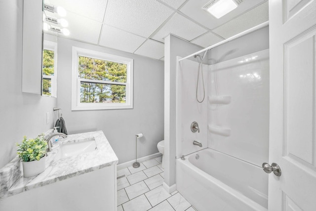 bathroom with toilet, a drop ceiling, baseboards, bathtub / shower combination, and vanity