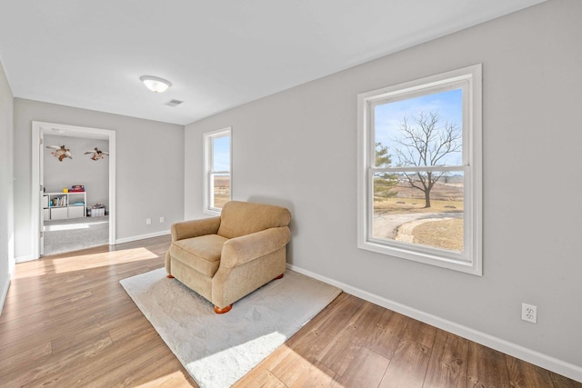 living area featuring visible vents, baseboards, and light wood finished floors