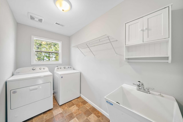 laundry area featuring a sink, visible vents, washing machine and dryer, and stone finish flooring