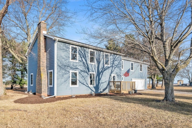 view of front facade with a garage, a front lawn, and a chimney