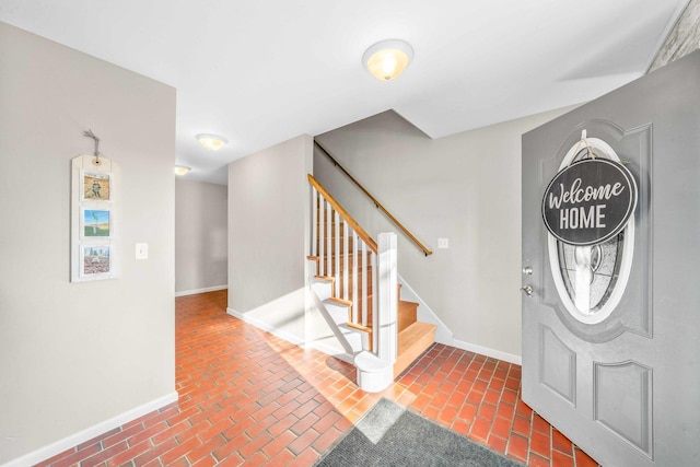 entrance foyer with brick floor, stairway, and baseboards