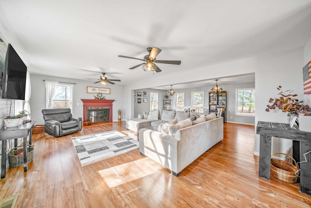 living area with a glass covered fireplace, a healthy amount of sunlight, visible vents, and light wood-style floors