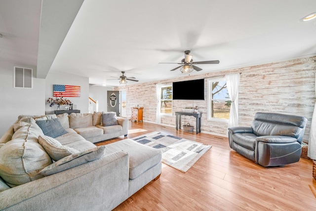 living area with a ceiling fan, visible vents, a fireplace, stairs, and light wood-style floors