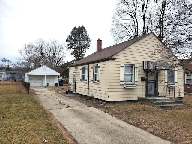 bungalow featuring an outbuilding, fence, a garage, and a chimney