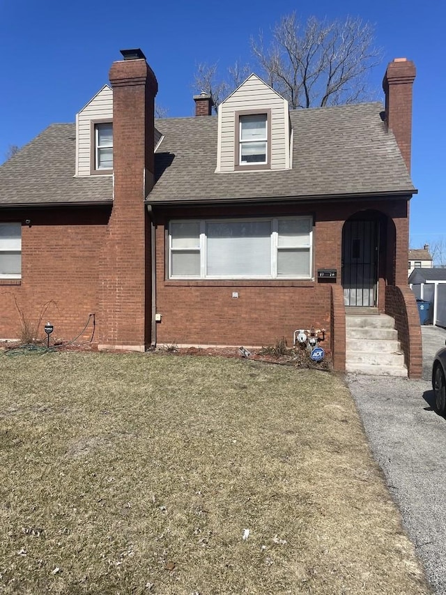 back of house featuring a shingled roof, brick siding, and a chimney