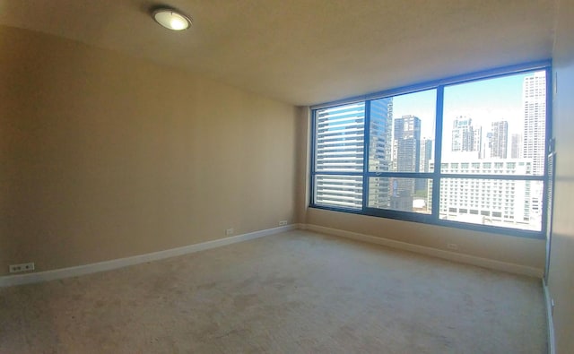 carpeted empty room with a view of city and baseboards