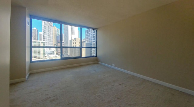 spare room featuring a city view, carpet, and baseboards