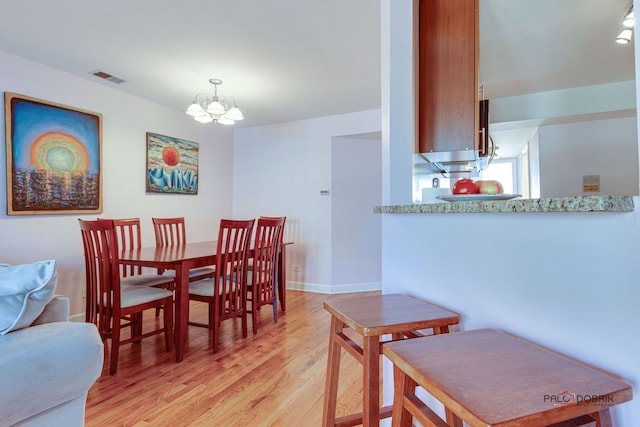 dining area with a chandelier, visible vents, light wood-type flooring, and baseboards