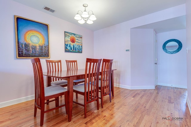 dining area with baseboards, visible vents, light wood finished floors, and a chandelier