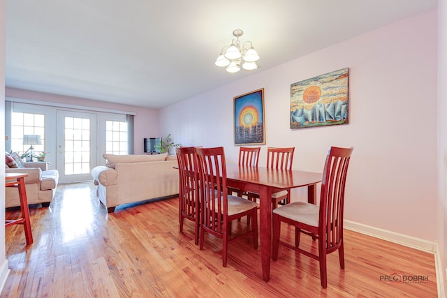 dining room with a notable chandelier, baseboards, and light wood finished floors