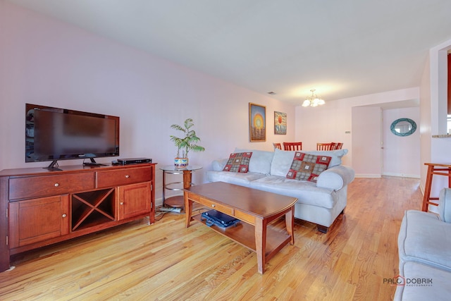 living room featuring light wood-style floors, baseboards, and a chandelier