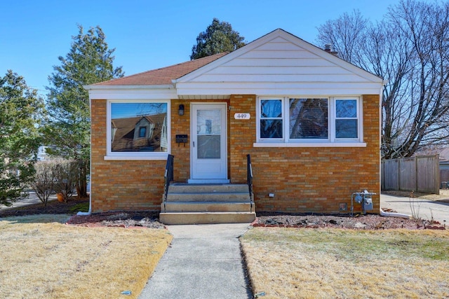 bungalow-style home featuring brick siding, a front lawn, and fence