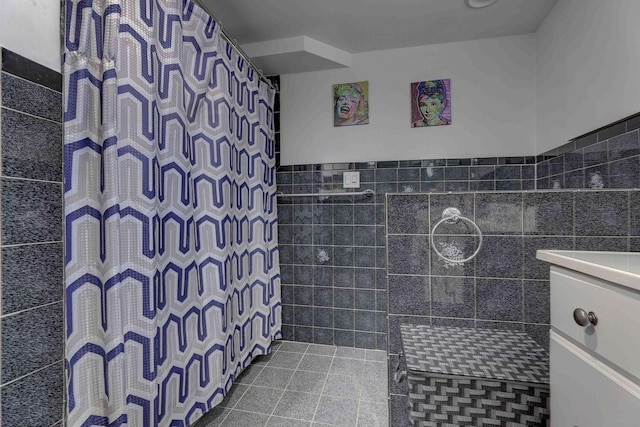 full bath featuring curtained shower, tile walls, vanity, and wainscoting