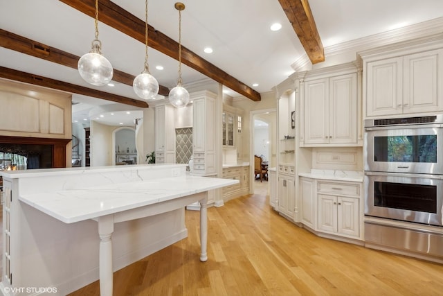 kitchen featuring light wood finished floors, beamed ceiling, hanging light fixtures, stainless steel double oven, and a warming drawer