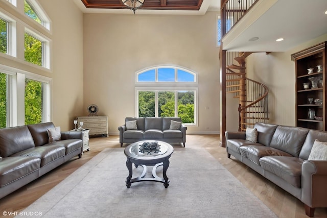 living area with stairway, baseboards, a high ceiling, and light wood-style flooring