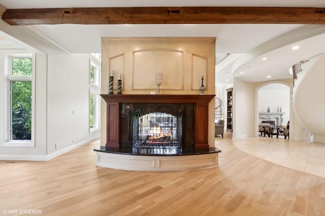 living area with a multi sided fireplace, beam ceiling, stairs, and light wood finished floors