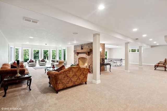 living area featuring a brick fireplace, plenty of natural light, light colored carpet, and visible vents