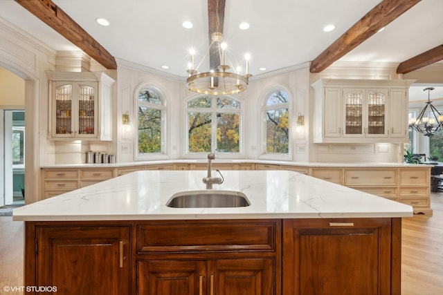 kitchen featuring beam ceiling, a notable chandelier, light stone countertops, and a sink