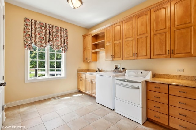 clothes washing area with visible vents, washer and clothes dryer, a sink, cabinet space, and baseboards