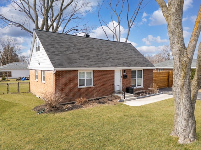 view of front of property with a front yard, fence, a shingled roof, entry steps, and brick siding