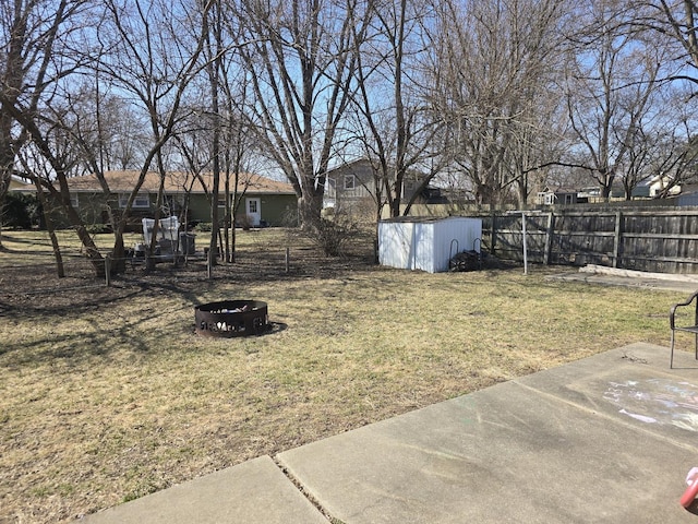 view of yard with an outbuilding, a shed, a fenced backyard, a fire pit, and a patio area