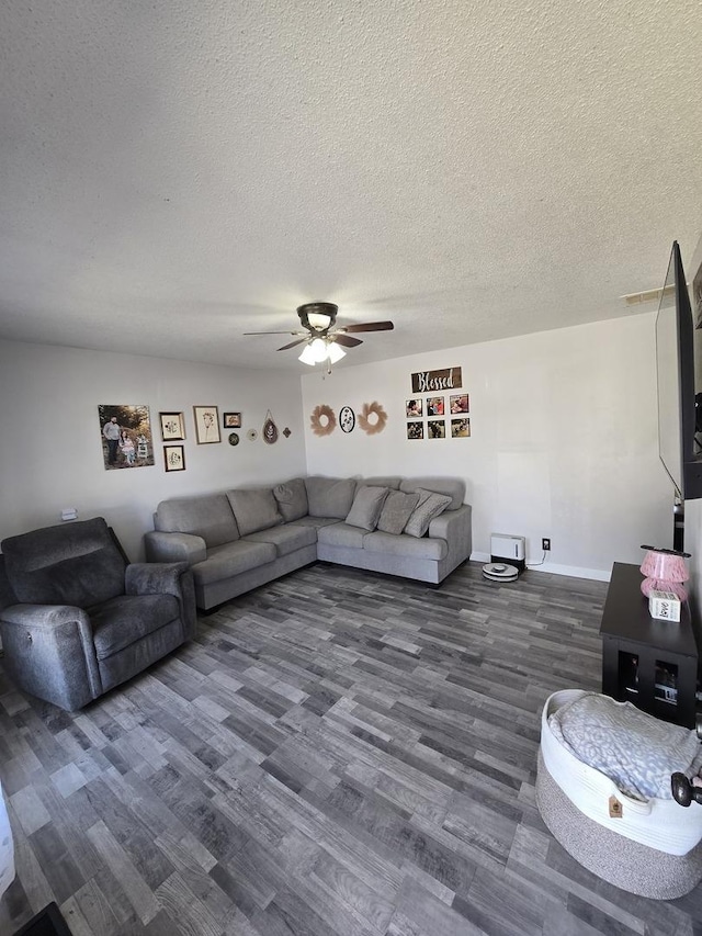 living area featuring baseboards, a textured ceiling, dark wood-type flooring, and a ceiling fan