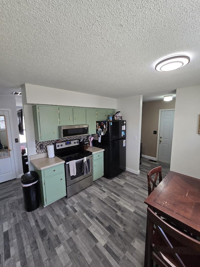 kitchen featuring green cabinetry, light countertops, dark wood-type flooring, appliances with stainless steel finishes, and a textured ceiling