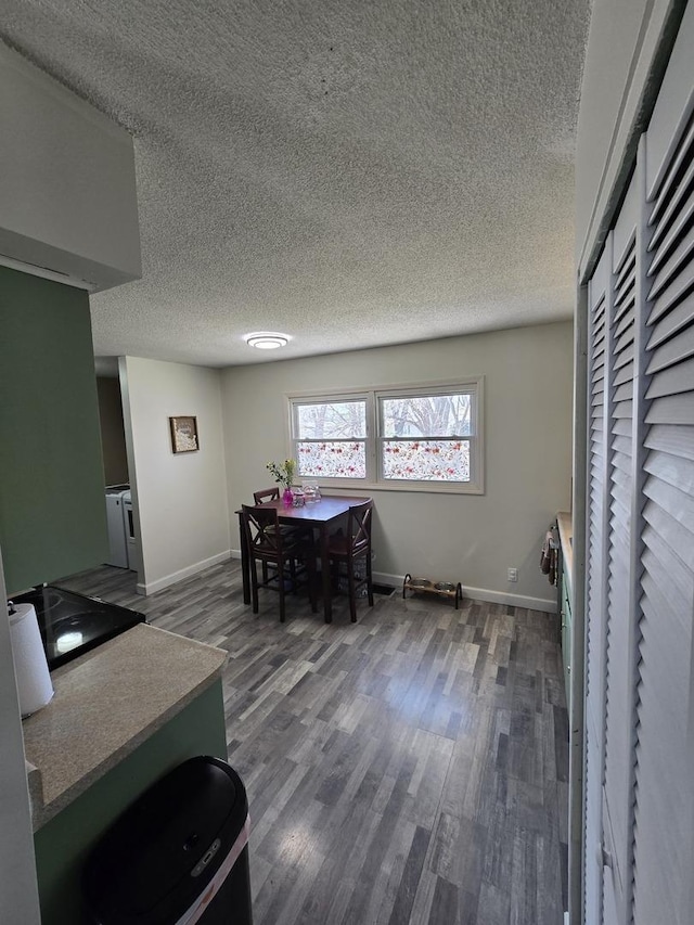 dining area with dark wood-type flooring, baseboards, and a textured ceiling