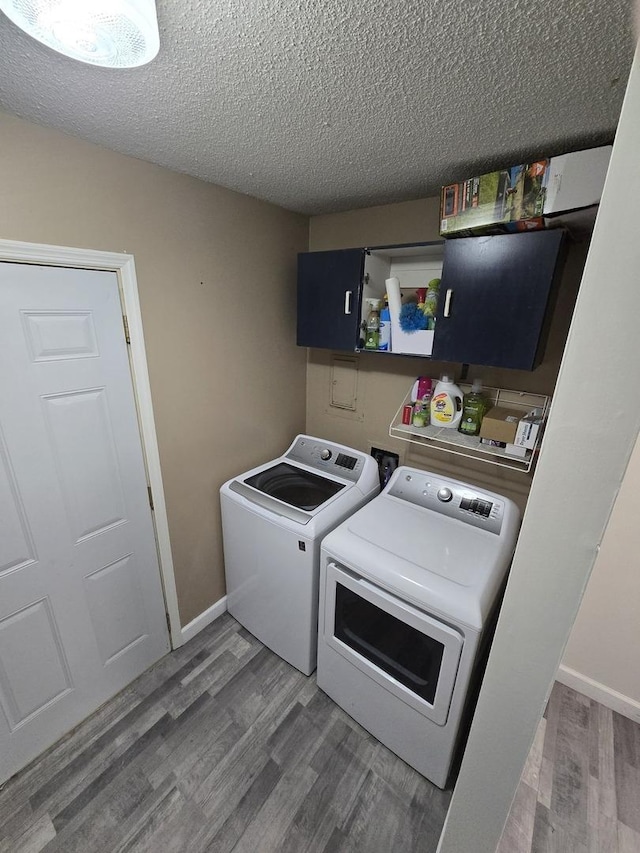 washroom featuring wood finished floors, baseboards, laundry area, a textured ceiling, and washer and dryer