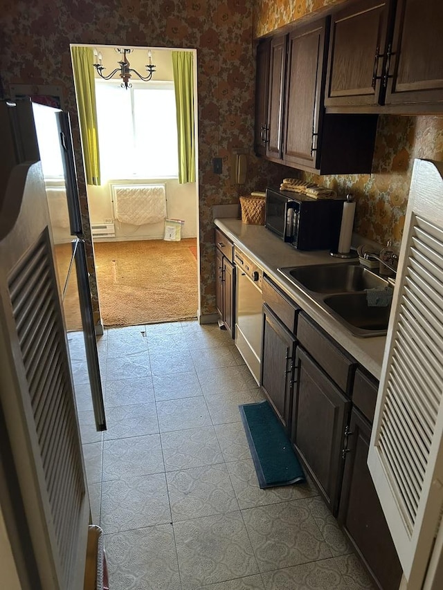 kitchen featuring tasteful backsplash, dark brown cabinets, light tile patterned floors, refrigerator, and a sink