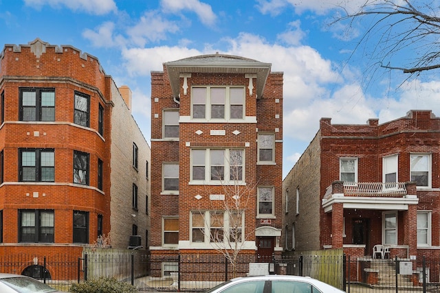 rear view of house featuring brick siding and a fenced front yard