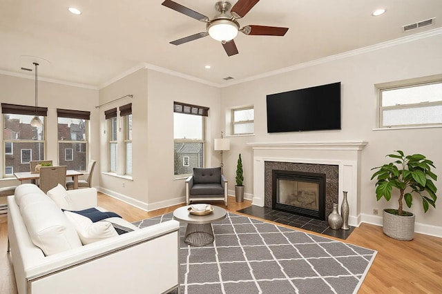 living room featuring visible vents, ornamental molding, baseboards, and wood finished floors