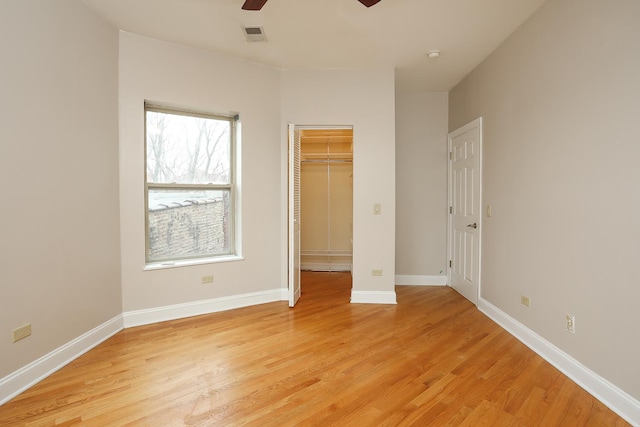 unfurnished bedroom featuring a spacious closet, light wood-type flooring, and baseboards