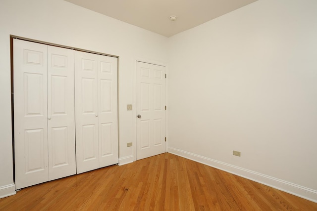 unfurnished bedroom with a closet, baseboards, and light wood-style floors